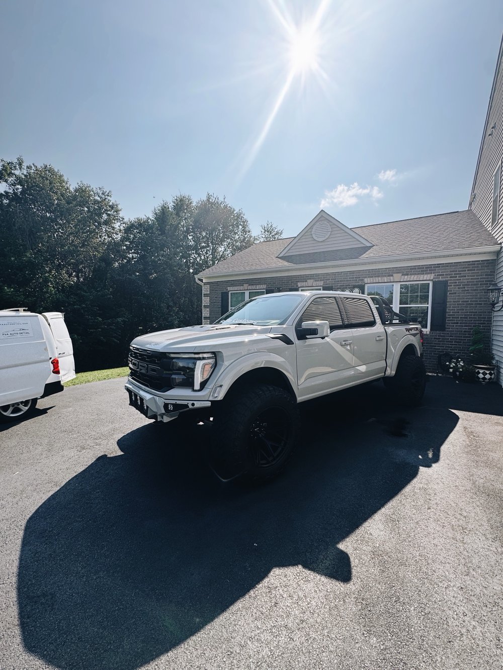 Lifted white Ford F-150 Raptor detailed on-site next to our van